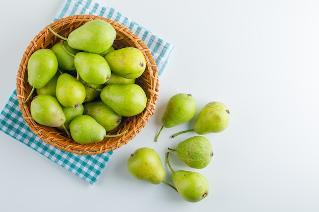 Green pears in a basket on white and kitchen towel. flat lay.