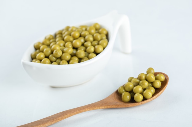 Green peas in wooden spoon and ceramic bowl