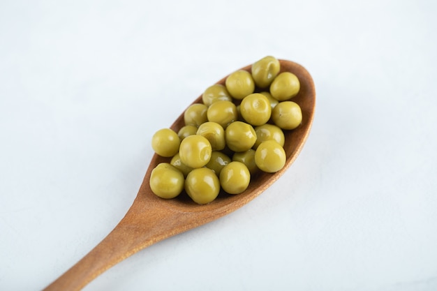 Green peas on wooden spoon