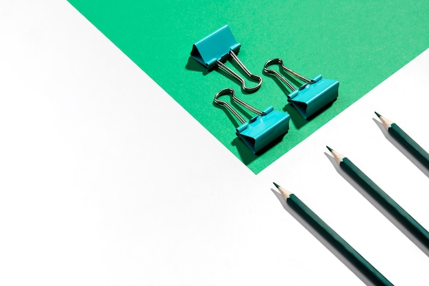 Free photo green pencils and metal binder clips for paper high view