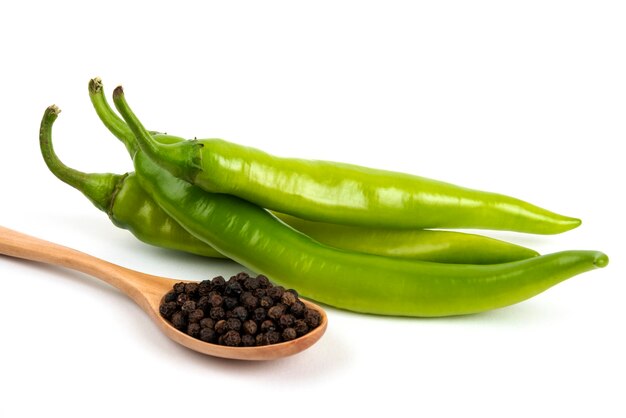 Green pepper and pepper grains on white.