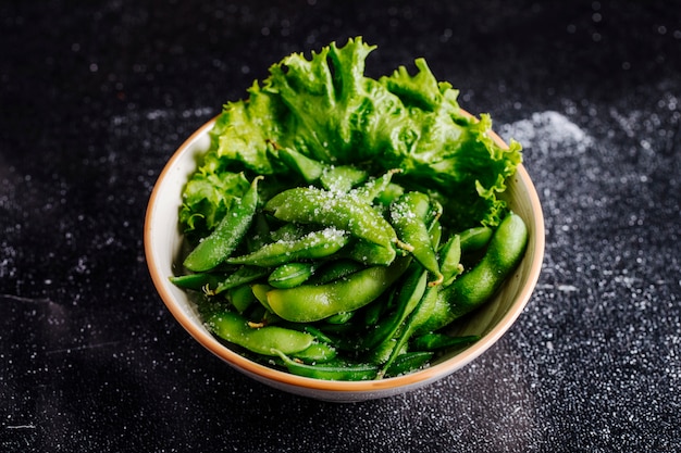 Green pickles, beans and lettuce inside a bowl.