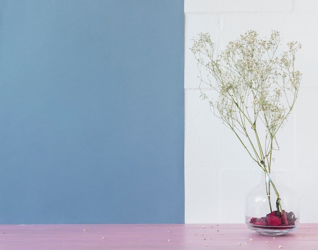 Green plant twigs in vase near brick wall