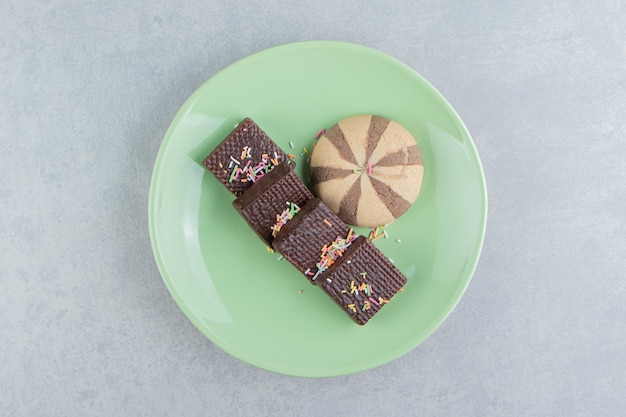 A green plate full of chocolate waffles .  