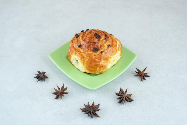 Un piatto verde di pasticceria dolce e anice stellato su bianco