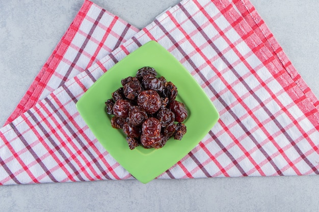 Free photo green plate of tasty dried dates on striped tablecloth.