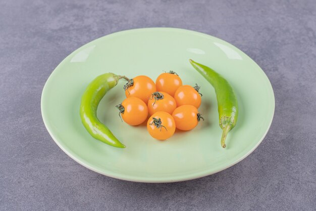 Зеленая тарелка с желтыми помидорами черри и перцем чили