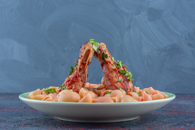 Un piatto verde con cosce di pollo fritte con maccheroni