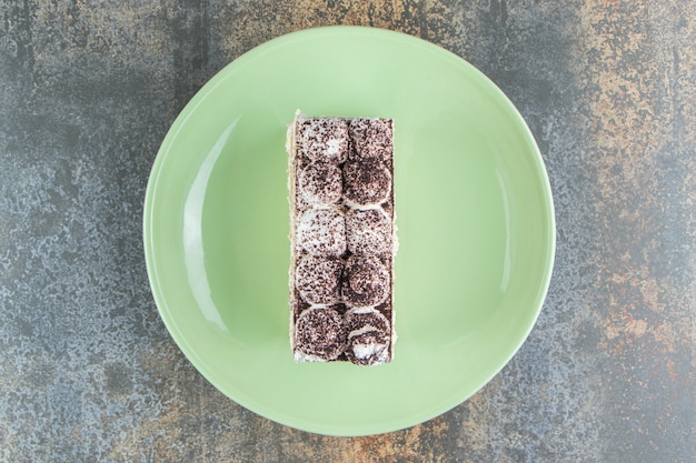 A green plate with piece of cake powdered of cacao 