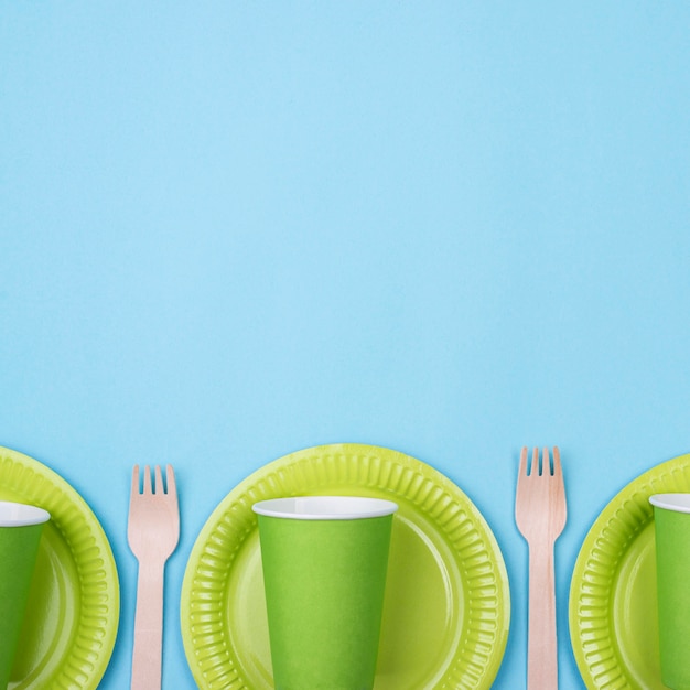 Green plates with cups and cutlery copy space