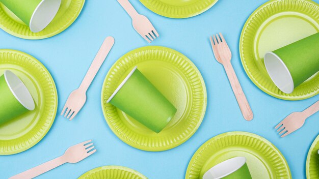 Green plates with cups and cutlery  flat lay