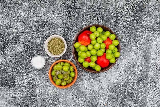 緑の梅と塩の小さなバーと粘土ボウルの桃と灰色のグランジの乾燥タイムトップビュー