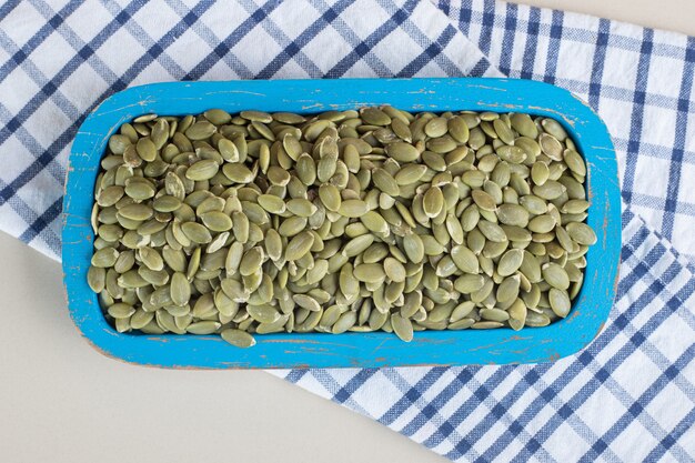 Green pumpkin seeds in a ceramic cup on concrete.