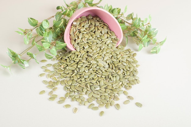 Free photo green pumpkin seeds in a container on concrete.