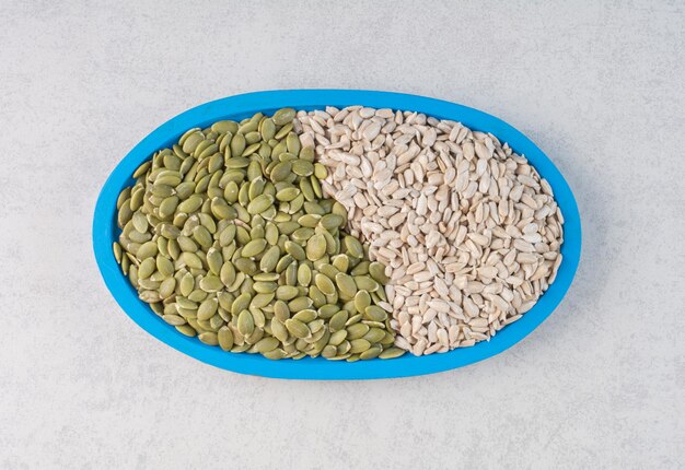 Green pumpkin and sunflower seeds in a platter. 