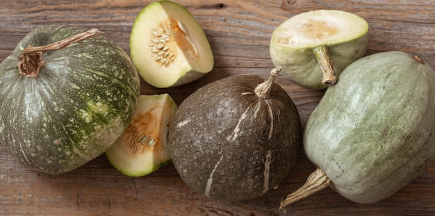 Green pumpkins on a background of wooden boards top view close up. Autumn harvest concept.