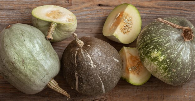 Green pumpkins on a background of wooden boards top view close up. Autumn harvest concept.