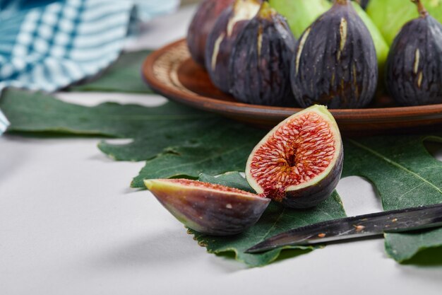 Green and purple figs in a wooden platter. 