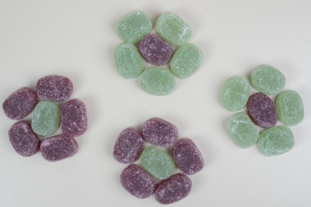 Зеленые и фиолетовые желейные конфеты на бежевой поверхности