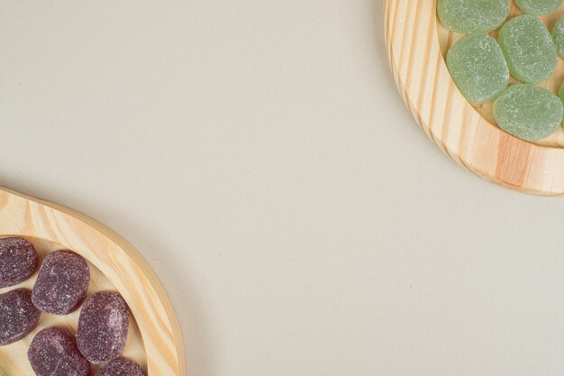 Зеленые и фиолетовые желейные конфеты на деревянных тарелках