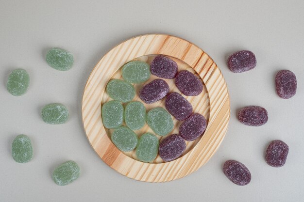 Foto gratuita caramelle di gelatina verde e viola su piatti di legno