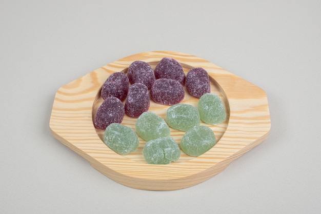 Foto gratuita caramelle di gelatina verde e viola su piatti di legno