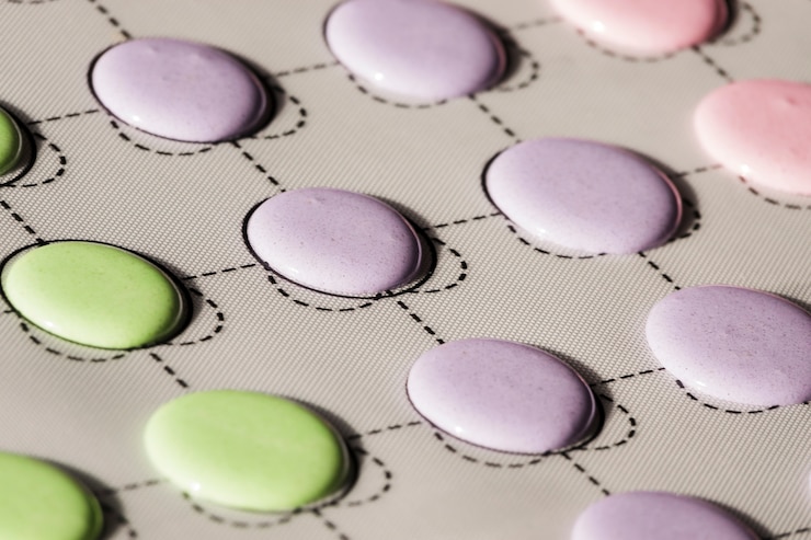 Free Photo green and purple macaroons shells on slip sheet