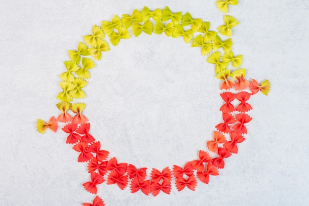 Free photo green and red farfalle pasta, on the marble surface