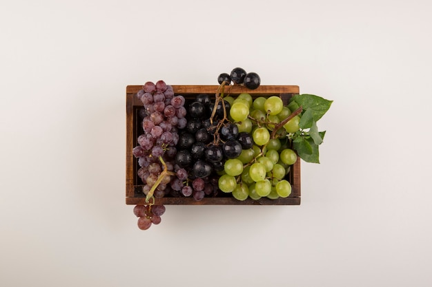 Free photo green and red grape bunches in a wooden box in the center