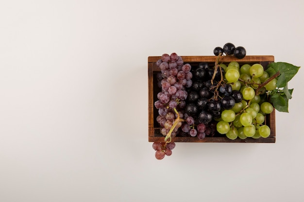 Green and red grape bunches in a wooden box in the center