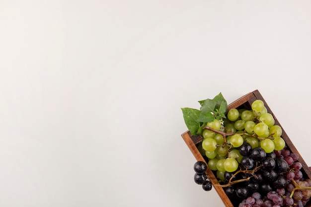 Green and red grape bunches in a wooden box in the corner