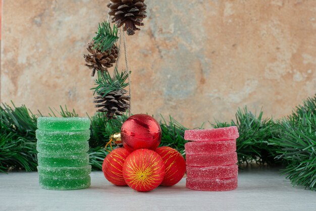 Green and red sugar marmalade with red Christmas balls on marble background. High quality photo