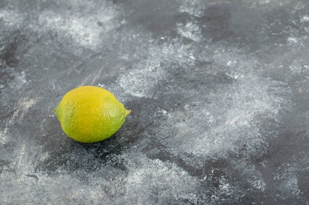 Зеленый спелый лимон на мраморной поверхности.