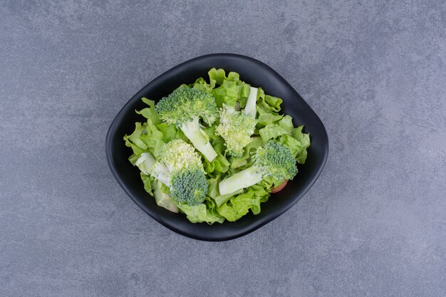 Green salad in a plate on blue surface