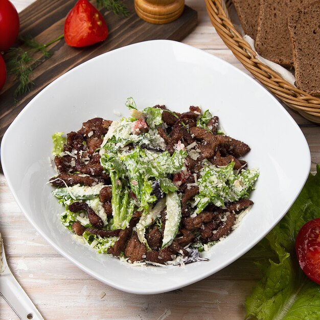 Зеленый салат с коричневыми грибами, рубленым мясом, листьями салата и пармезаном