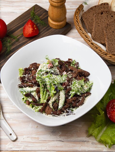 Green salad with brown mushrooms, chopped meat, lettuce and parmesan