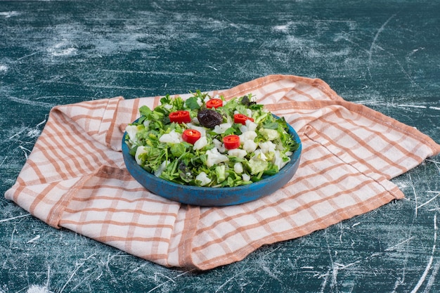 Free photo green salad with chopped lettuce on blue surface.