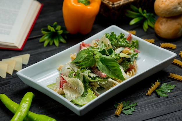 Зеленый салат с листьями свежей мяты и нарезанным пармезаном в квадратной тарелке.