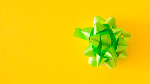 Green satin ribbon bow on yellow background