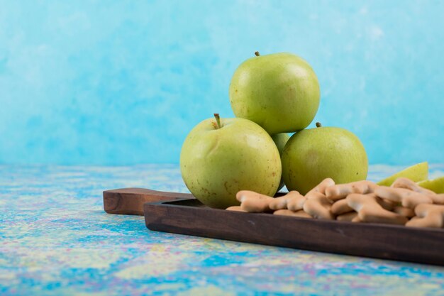 Green sliced apples with crackers on the wooden board,  side view