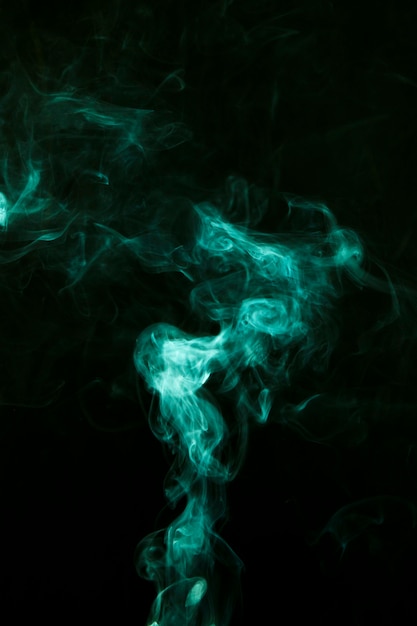 Free photo green smoke moves over against black dark background