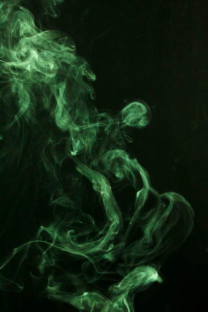 Зеленый дым распространяется на черном фоне