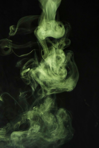 Бесплатное фото Зеленый дым кружится на черном фоне