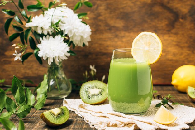 Green smoothie next to vase of flowers