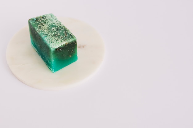 Free photo green soap bar on circular board over white surface