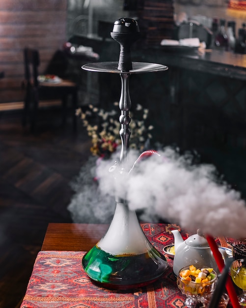 Green steaming hookah on the table tea side view