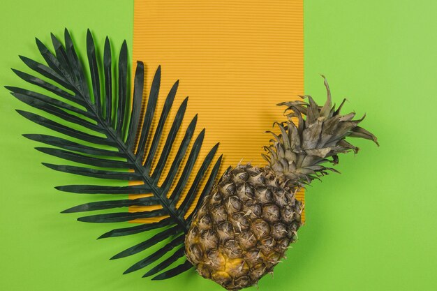 Green surface with blank paper and pineapple