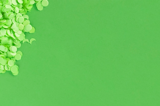 Free photo green surface with paper confetti