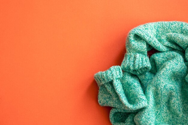 Green sweater on orange background flat lay