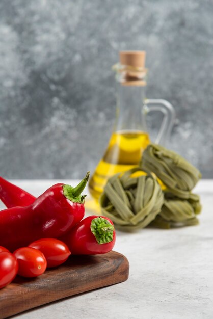 Green tagliatelle, vegetables and olive oil on marble background.